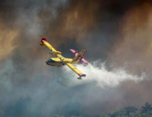 A yellow plane dropping water on a wildfire. Firefighters are at great risk of dehydration and may need to supplement with natural electrolytes. 